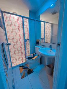 a blue bathroom with a toilet and a sink at Azure Staycation in Manila