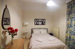 - une chambre avec un lit et un vase avec des fleurs rouges dans l'établissement Georgia's lakeside house, à Kastoria