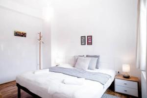 a white bedroom with a bed and a table at Stylish and comfy apartment for 6 guests in Budapest