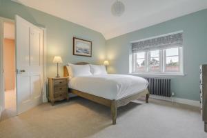 a bedroom with a white bed and a window at Gardeners Cottage - Hot Tub Packages Available in Market Harborough