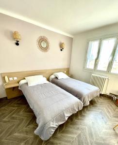 a bedroom with two beds and a mirror on the wall at Hôtel Colisée-Verdun Centre Gare Saint-Roch in Montpellier