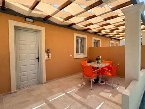 a dining room with orange chairs and a table at Summerscape Studios and Apartments in Corfu