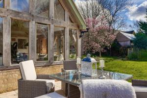 a patio with a glass table and chairs at Honeysuckle Cottage - Hot Tub Packages Available in Weston Subedge