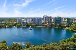 a lake in front of a city with a sailboat at Stylish Urban Retreat Steps from Lake Eola in Orlando