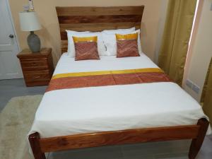 a bedroom with a bed with a wooden headboard and pillows at JEMMROSE SUITES in Choc