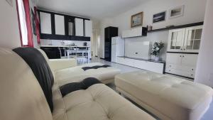un soggiorno con 2 divani bianchi e una cucina di Villa Isola Bella - Appartamento Bianconero a Mògoro