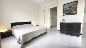 una camera bianca con un letto, un comò e un dipinto di Villa Isola Bella - Appartamento Bianconero a Mògoro