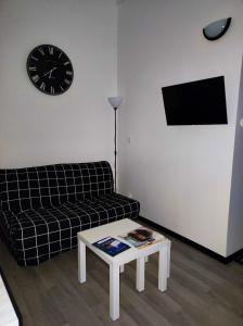 sala de estar con sofá y reloj en la pared en Studio avec wifi a Chateau Thierry en Château-Thierry