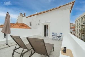 - une terrasse avec des chaises et un parasol dans un bâtiment blanc dans l'établissement Setubal Terrace apartments, à Setúbal