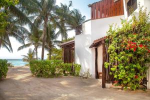 a house on the beach with a fence and flowers at Casa Colibrí Tankah in Tulum