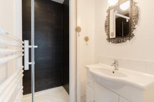 La salle de bains blanche est pourvue d'un lavabo et d'un miroir. dans l'établissement Studio et appartements Sainte Catherine, à Honfleur