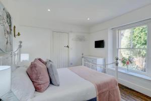 a white bedroom with a bed and a window at Seven Acres Cottage with Parking in Bath