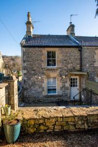 a stone house with a stone wall in front of it at Seven Acres Cottage with Parking in Bath