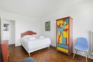 a bedroom with a bed and a colorful dresser at Amazing panoramic view facing Parc de La Villette - Apartment 4P in Paris