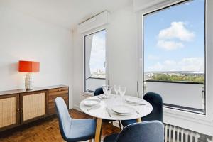 uma sala de jantar com mesa e cadeiras e janelas grandes em Amazing panoramic view facing Parc de La Villette - Apartment 4P em Paris