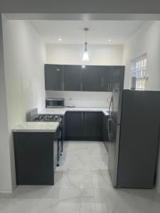 a kitchen with black and white cabinets and a refrigerator at Faith moves mountains in Ocho Rios