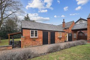 una casa de ladrillo con puertas negras y una valla en Squirrel Lodge - 2 Bed Country Home en Market Harborough