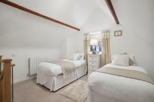 a white bedroom with two beds and a dresser at Squirrel Lodge - 2 Bed Country Home in Market Harborough