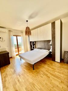 een slaapkamer met een wit bed en een houten vloer bij La Casa Sul Lago in Passignano sul Trasimeno