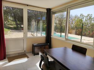 ein Esszimmer mit einem Tisch und 2 Fenstern in der Unterkunft Maison confortable à Ansouis dans Le Luberon in Ansouis