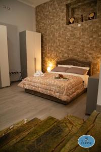 a bedroom with a large bed and a brick wall at Le Dimore di Ulisse a Gela - Casa vacanza B&B - La casa di Ulisse in Gela