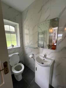 biała łazienka z toaletą i umywalką w obiekcie Woodville Lodge Guesthouse w Killarney