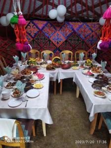 een set tafels met borden met voedsel erop bij Zalkar Yurt Camp in Song-Kul