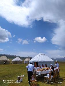 een groep mensen die aan een tafel in een tent zitten bij Zalkar Yurt Camp in Song-Kul
