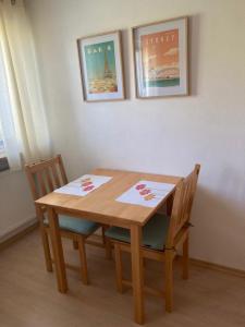 a wooden table with two chairs and two pictures on the wall at FeWo 49 in Goldkronach