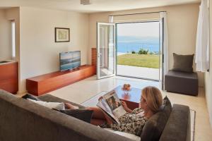a woman sitting on a couch reading a book at Il Leccio - Luxury Resort Portofino Monte in Santa Margherita Ligure