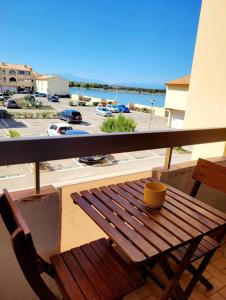 a wooden bench on a balcony with a view of a parking lot at Appartement climatisé à deux pas de la plage in Port Leucate