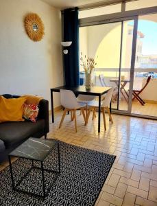a living room with a couch and a table and chairs at Appartement climatisé à deux pas de la plage in Port Leucate