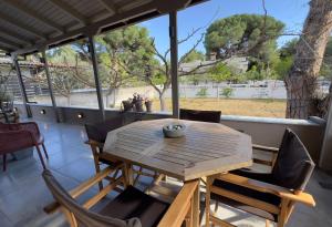 una mesa de madera y sillas en un porche con un árbol en Boutique Villa Loigi Shoinias, en Atenas