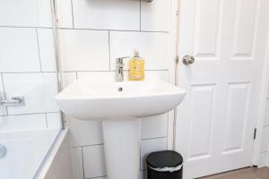 a white sink in a bathroom with a door at Great 3 bed Handbridge home - Sleeps 6 - EV Charger in Hough Green +23 photos