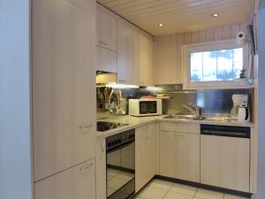 kuchnia z białymi szafkami, zlewem i kuchenką mikrofalową w obiekcie Holiday Home Chalet Guldeli by Interhome w mieście Kandergrund