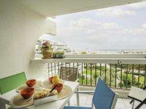 a table with a plate of food on a balcony at Studio Ulysse Plage-5 by Interhome in La Grande Motte