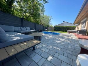 patio z kanapą i stołami oraz basenem w obiekcie Zen Garden Vendégház Siófok w Siófoku