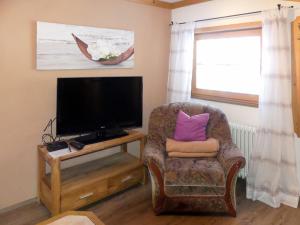 ein Wohnzimmer mit einem Stuhl und einem Flachbild-TV in der Unterkunft Apartment Kammerlander - NKI135 by Interhome in Neukirchen am Großvenediger