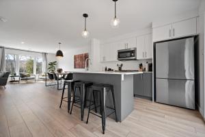 a kitchen with white cabinets and bar stools at Maison Oasis by Rendez-Vous Mont-Tremblant in Saint-Faustin