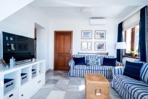 a living room with blue and white couches and a tv at Tóparti villa, közvetlen vízkapcsolattal in Siófok
