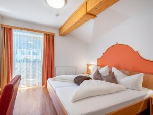 ein Schlafzimmer mit einem weißen Bett mit einem orangefarbenen Kopfteil und einem Fenster in der Unterkunft Apartment Rosa - MHO133 by Interhome in Mayrhofen