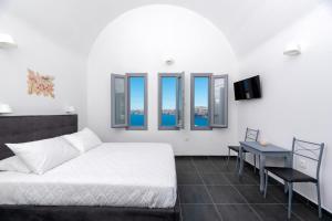 a bedroom with a bed and a table and windows at Pancratium Villas & Suites in Akrotiri