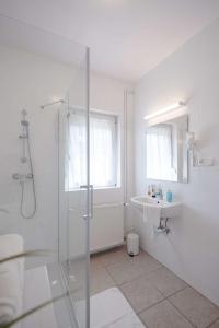 uma casa de banho branca com um chuveiro e um lavatório. em Teljesen felújított, szépen berendezett nyaraló em Balatonfenyves