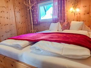 um quarto com uma cama grande com lençóis vermelhos e brancos em Chalet Wegscheider - MHO326 by Interhome em Mayrhofen