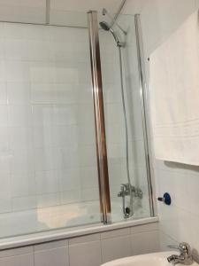 a shower with a glass door next to a sink at Alojamiento Seda in Alcalá de Guadaira