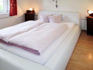 a white bed with white sheets and pink pillows at Chalet Jenneweinhütte - ZAZ408 by Interhome in Zell am Ziller