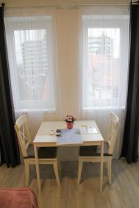 een tafel en stoelen in een kamer met 2 ramen bij ****Heviz Springs Apartments in Hévíz