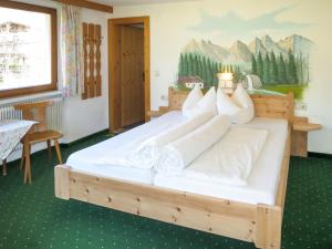 een slaapkamer met een groot bed met witte lakens en kussens bij Apartment Heisenhaus - MHO680 by Interhome in Ramsau im Zillertal