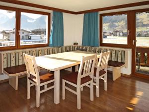 een eetkamer met een tafel, stoelen en ramen bij Apartment Heisenhaus - MHO680 by Interhome in Ramsau im Zillertal