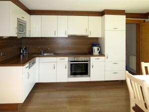 een witte keuken met witte kasten en een wastafel bij Apartment Heisenhaus - MHO680 by Interhome in Ramsau im Zillertal